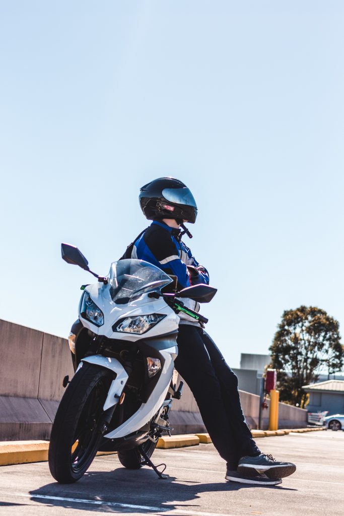 Homme accoudé sur une moto blanche